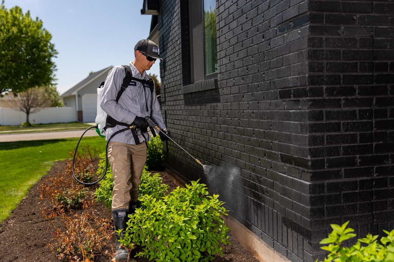 Technician spraying home exterior foundation