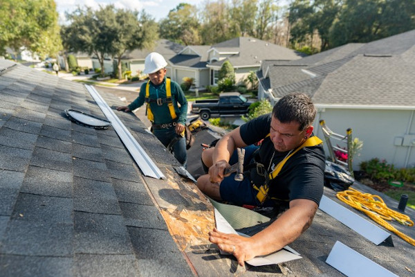 Roofer inspecting shingles for damage